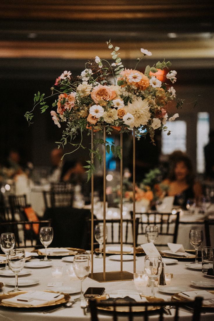 a tall vase filled with flowers sitting on top of a white table cloth covered table