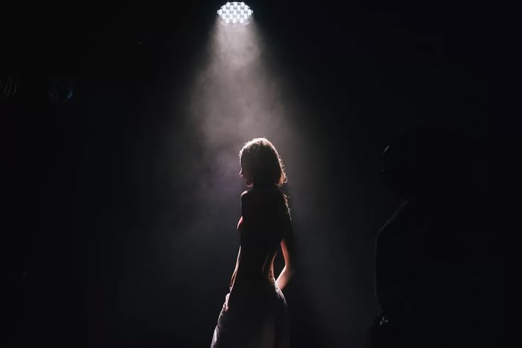 a woman standing in front of a spotlight