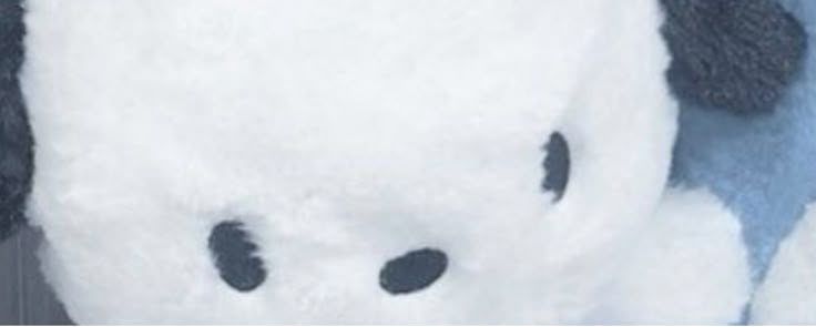 a white stuffed animal with black spots on it's face and nose, sitting in front of a blue background