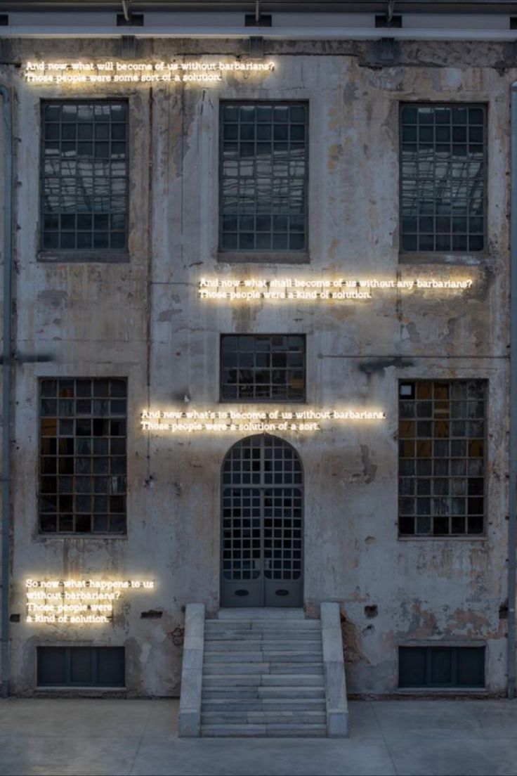 an old building with lots of windows and lights on the outside wall, along with steps leading up to it