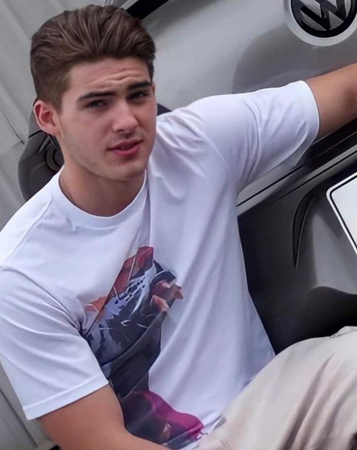 a young man sitting on the back of a car next to a vw sign