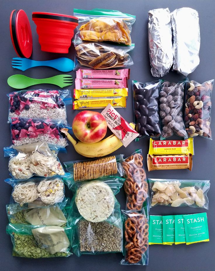 an assortment of food is laid out on a gray surface with plastic forks and spoons