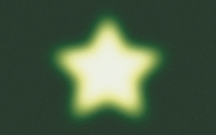 a blurry image of a white star on a green background with the light reflecting off it's side