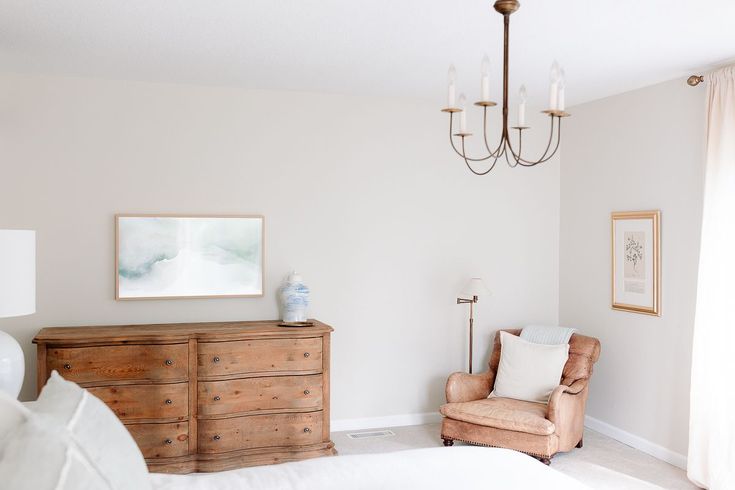 a bedroom with a chair, dresser and chandelier hanging from it's ceiling