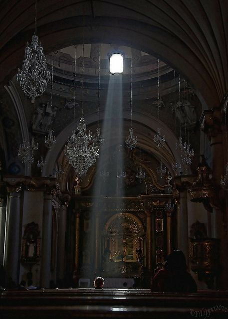 the light shines brightly in an old church with chandeliers hanging from the ceiling