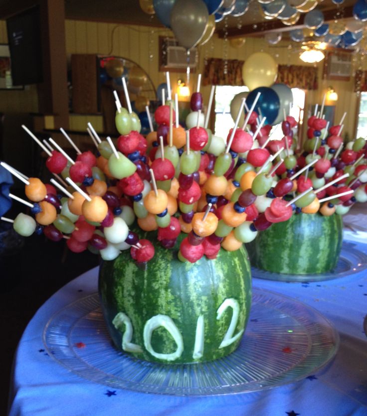 two watermelon vases filled with fruit and sticks in the shape of numbers