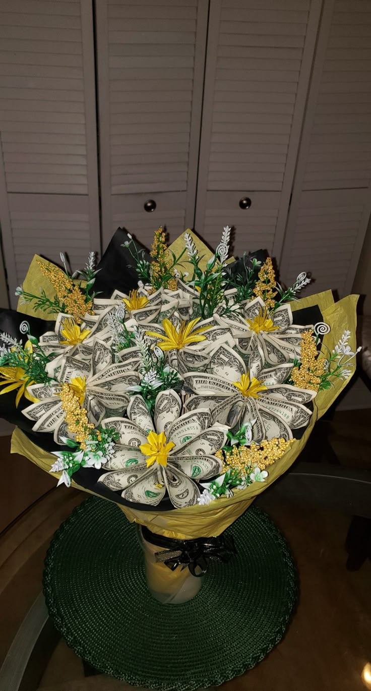 a vase filled with money and flowers on top of a green place mat in front of two white doors