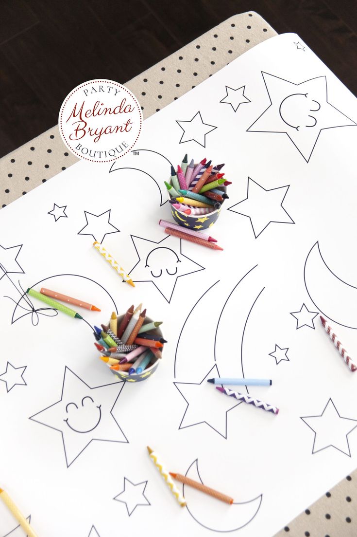 some crayons are laying on top of a white paper with stars and crescents