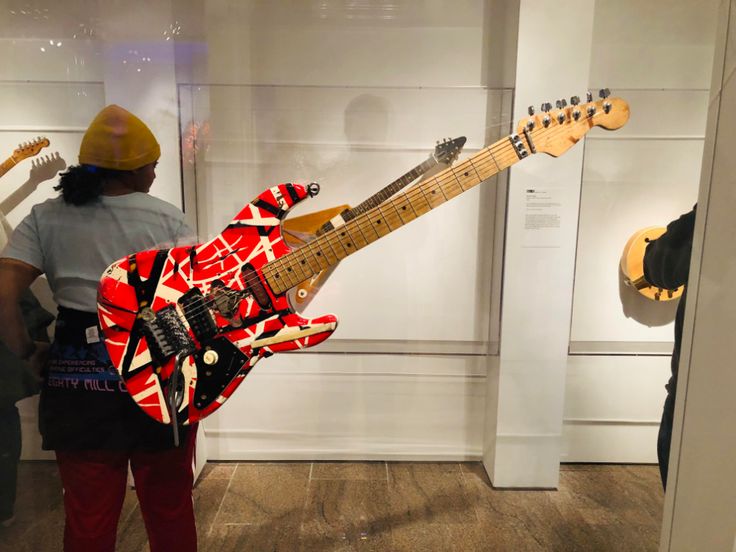 a man is looking at an electric guitar on display