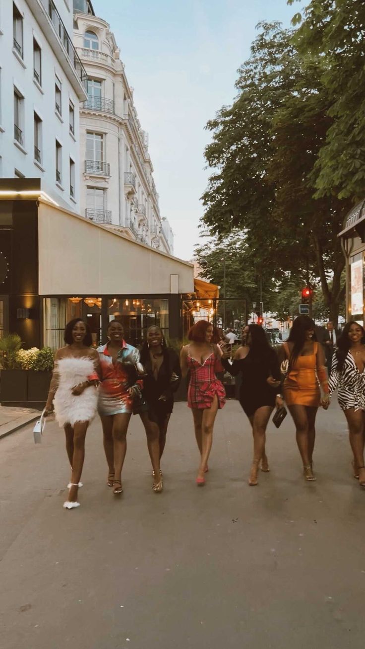 several women walking down the street in front of tall buildings