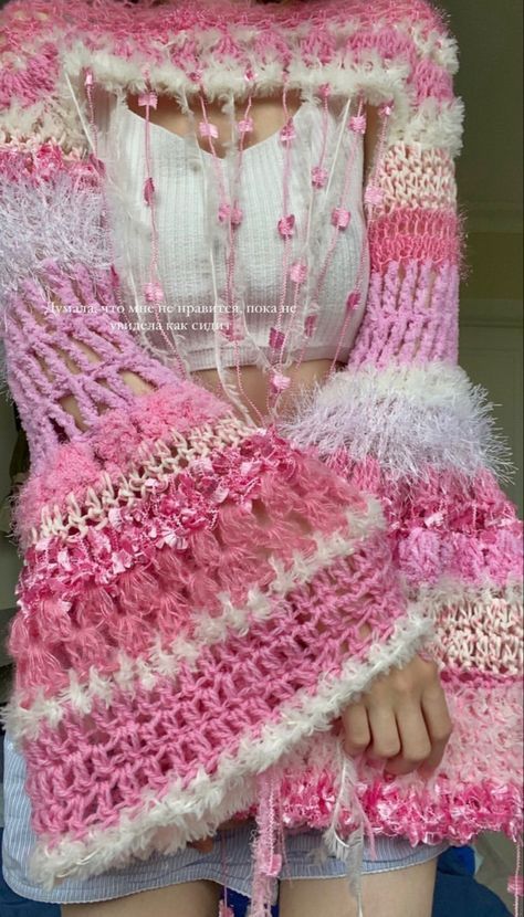 a woman wearing a pink and white crocheted shawl with fringes on it