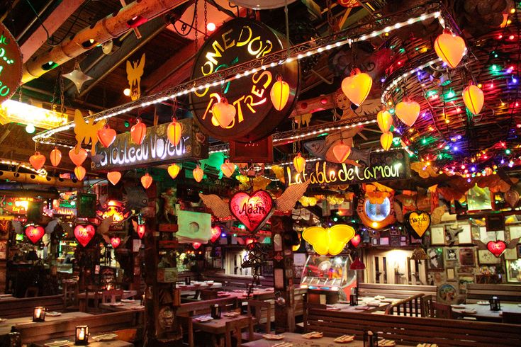 the inside of a restaurant with many lights hanging from the ceiling and tables in front of them