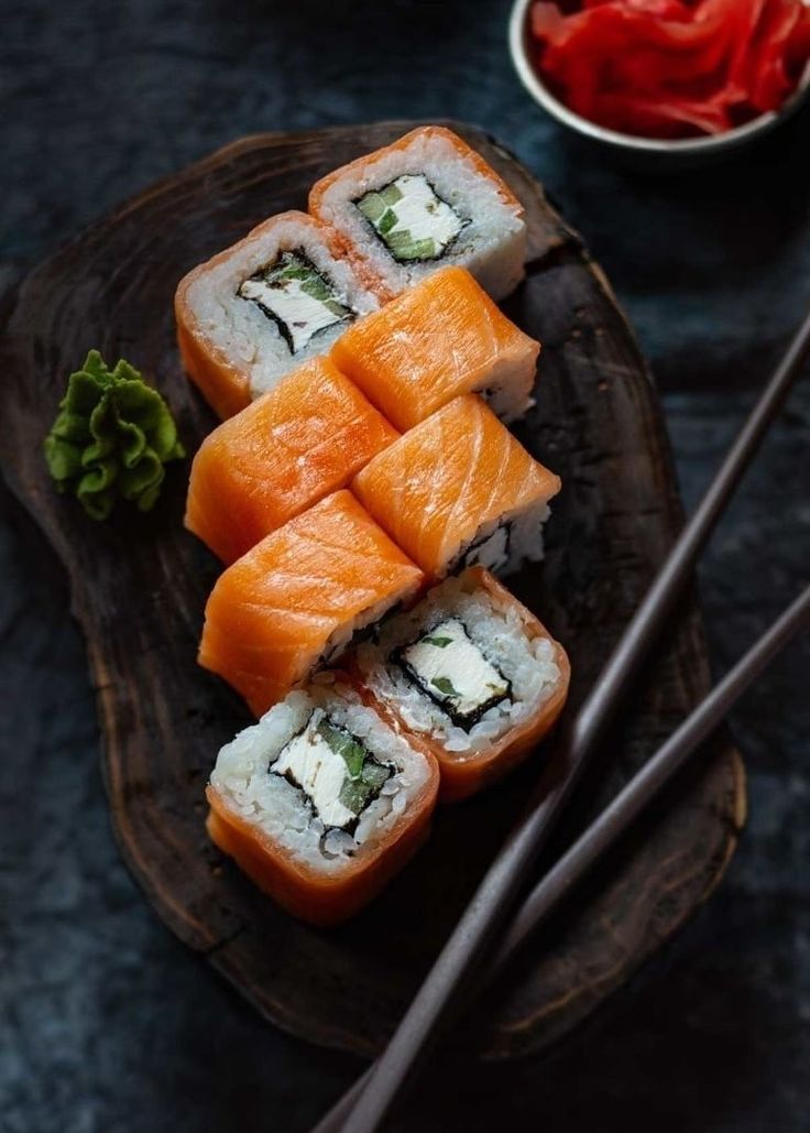 sushi on a wooden plate with chopsticks next to it