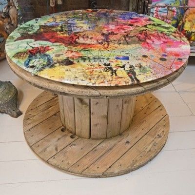 a round table made out of wood and painted with various colors on it, sitting in a store