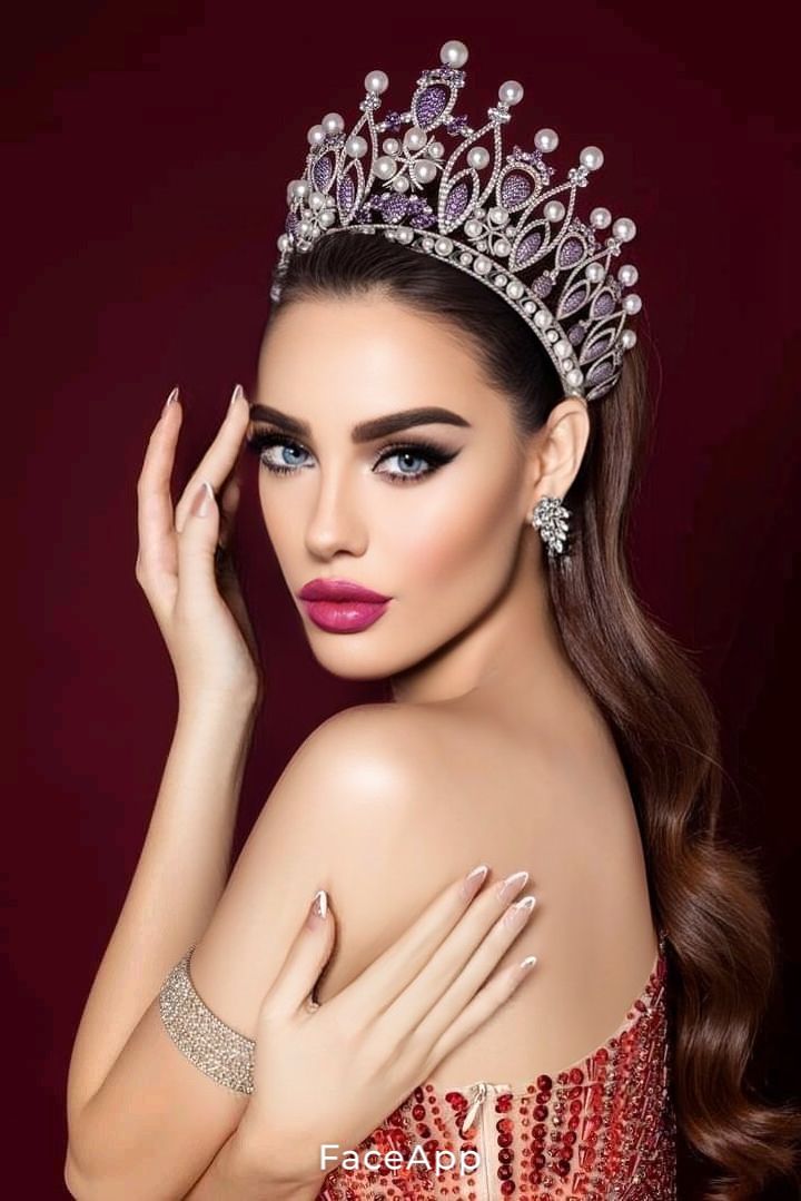 a beautiful woman wearing a tiara and holding her hand up to her face while posing for the camera