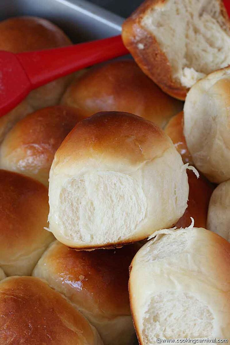 bread rolls with butter on them sitting in a red bowl, ready to be baked