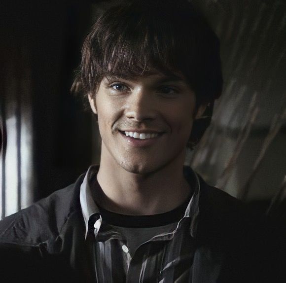 a smiling young man standing in front of a mirror