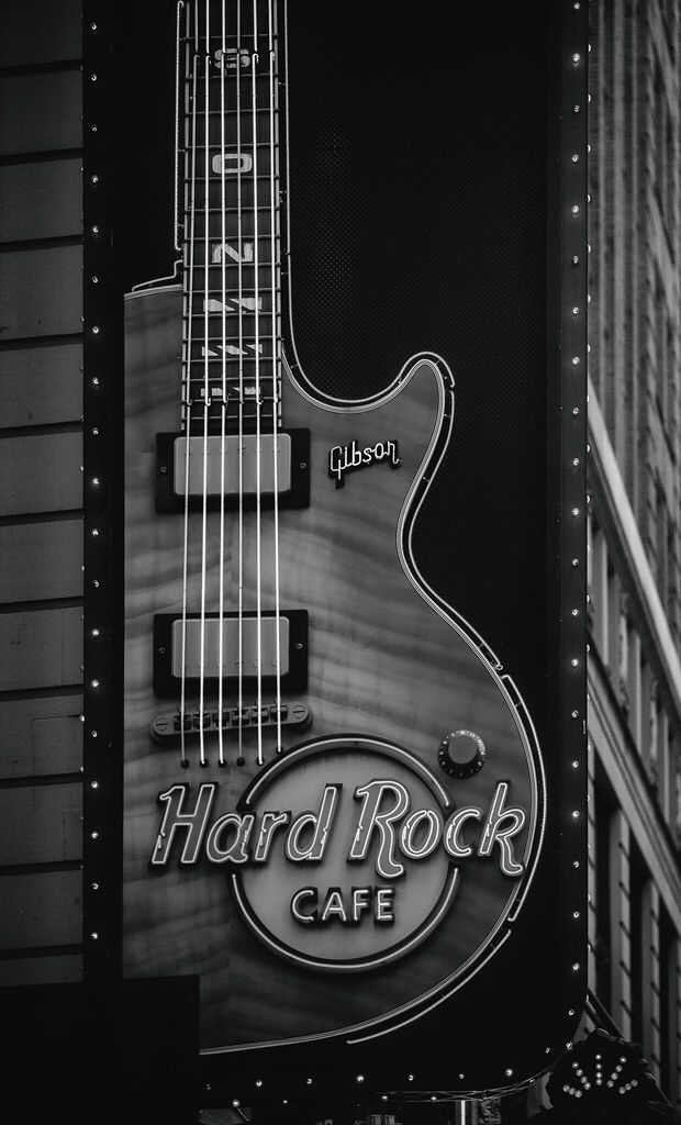 a black and white photo of a hard rock cafe sign with a guitar on it