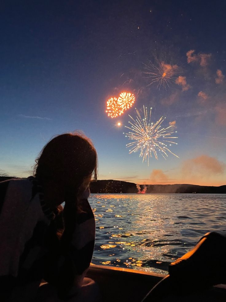 a person sitting on a boat watching fireworks