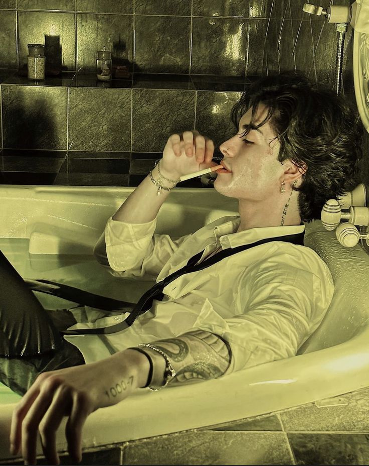 a man laying in a bathtub with his mouth open and drinking from a straw