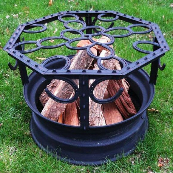 an outdoor fire pit made out of metal and wood with logs in the center on grass