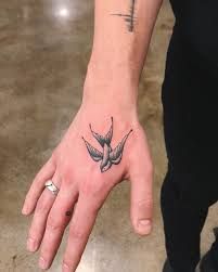 a person's hand with a bird tattoo on it