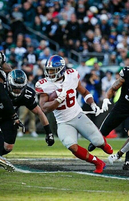 a football player running with the ball in his hand and other players on the field behind him