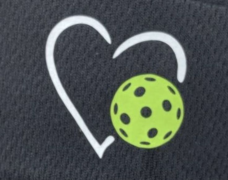 a black hat with a green ball in the shape of a heart on it's side