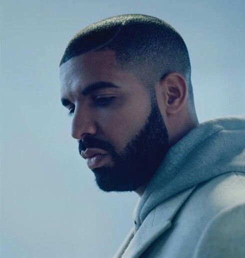 a close up of a person with a beard wearing a hoodie and looking down