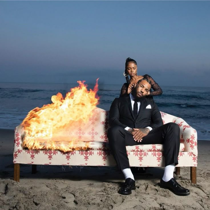 a man and woman sitting on a couch in front of a fire