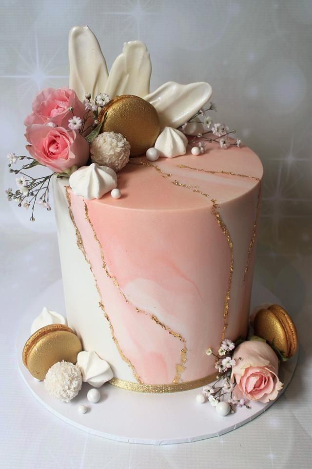 a pink marble cake with gold accents and flowers on the top, sitting on a white plate