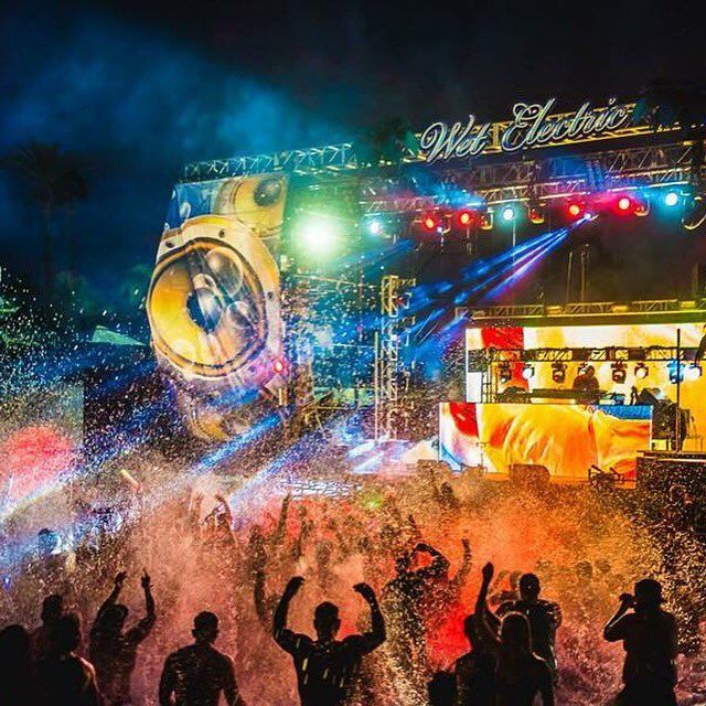 people standing in front of a stage with colored lights and confetti on it