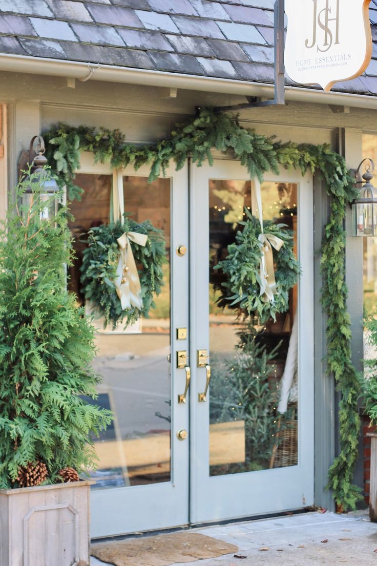 two green wreaths on the front door of a store