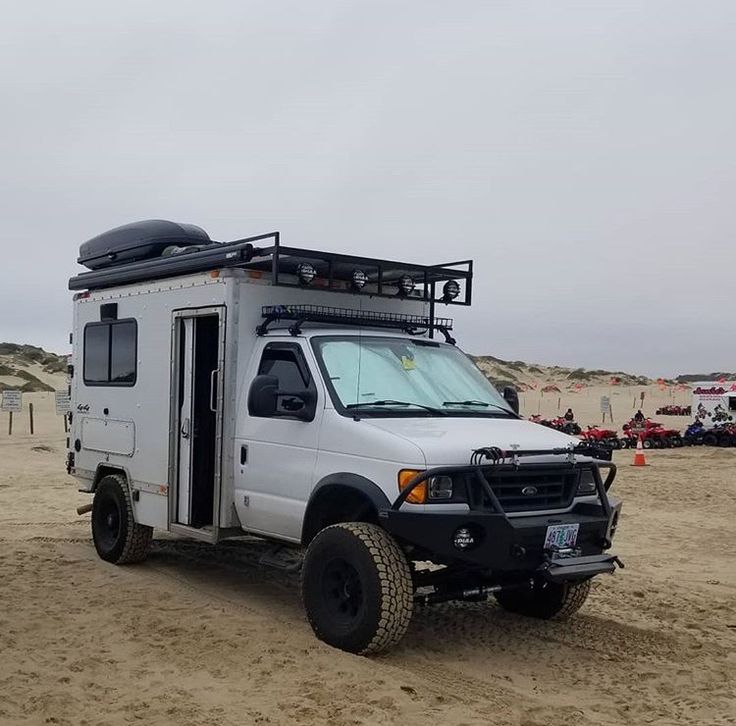 a white truck parked on top of a sandy beach