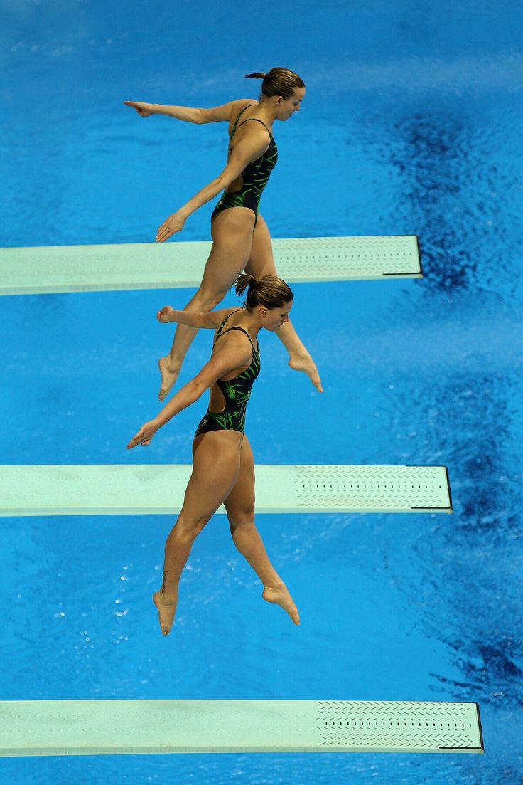 two women in bathing suits jumping into the water