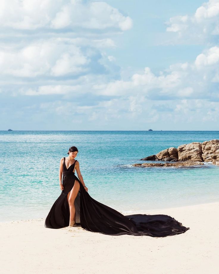 a woman in a black dress on the beach