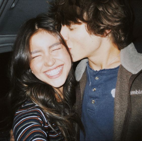 a young man and woman are kissing in the back seat of a car, with their eyes close to each other