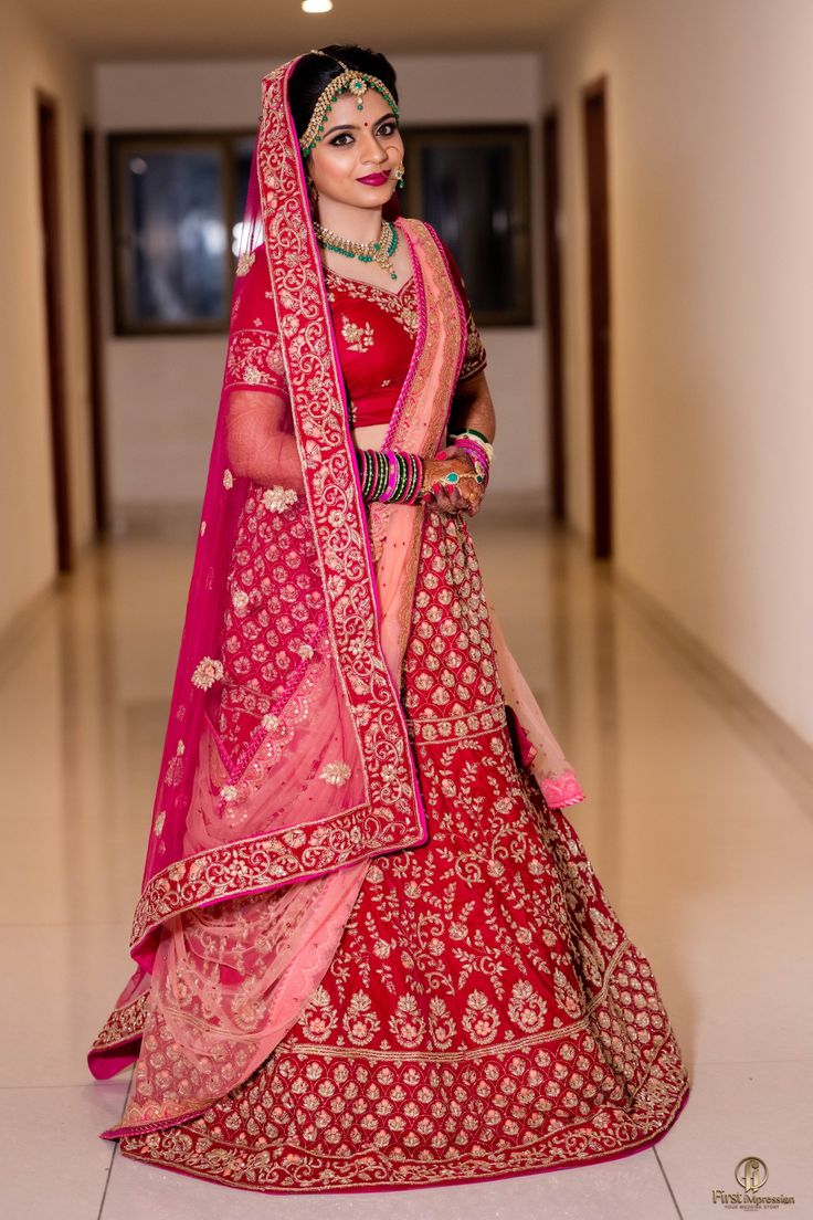 a woman in a red and pink bridal gown posing for the camera with her hand on her hip