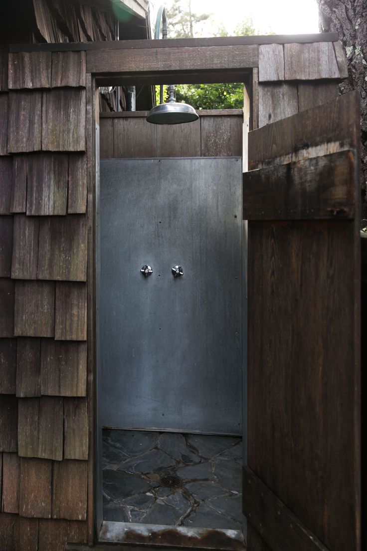 an open door to a wooden shed with stone flooring and shingles on the roof