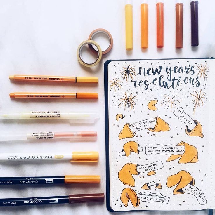 the new year's resolution is written on a notebook surrounded by markers and pens