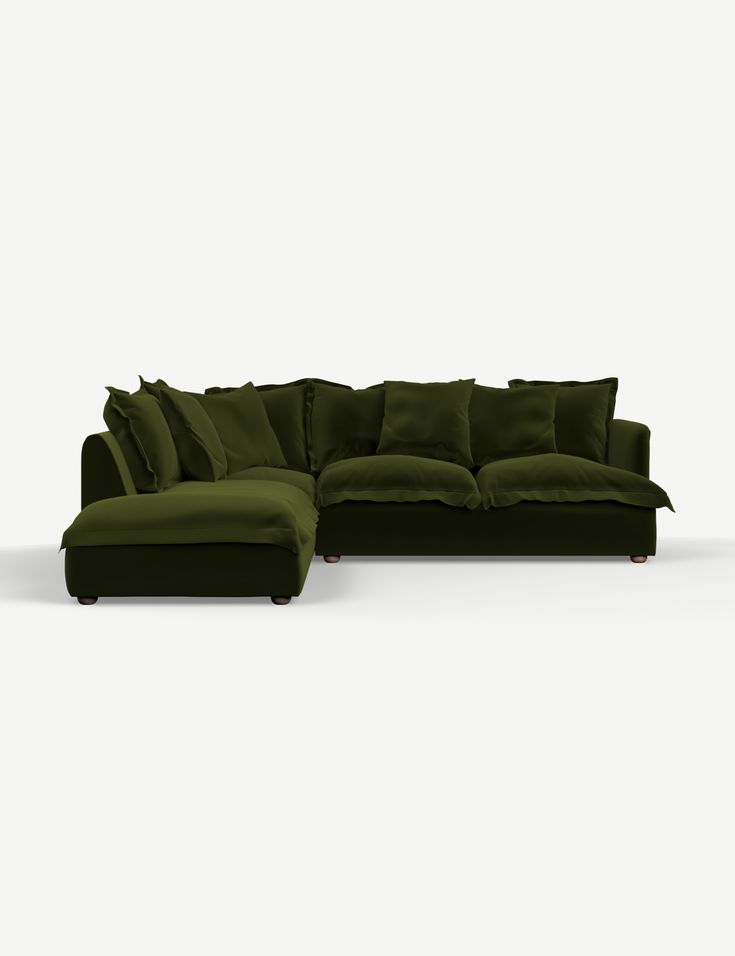 a large green couch with pillows on it's back and side facing away from the camera