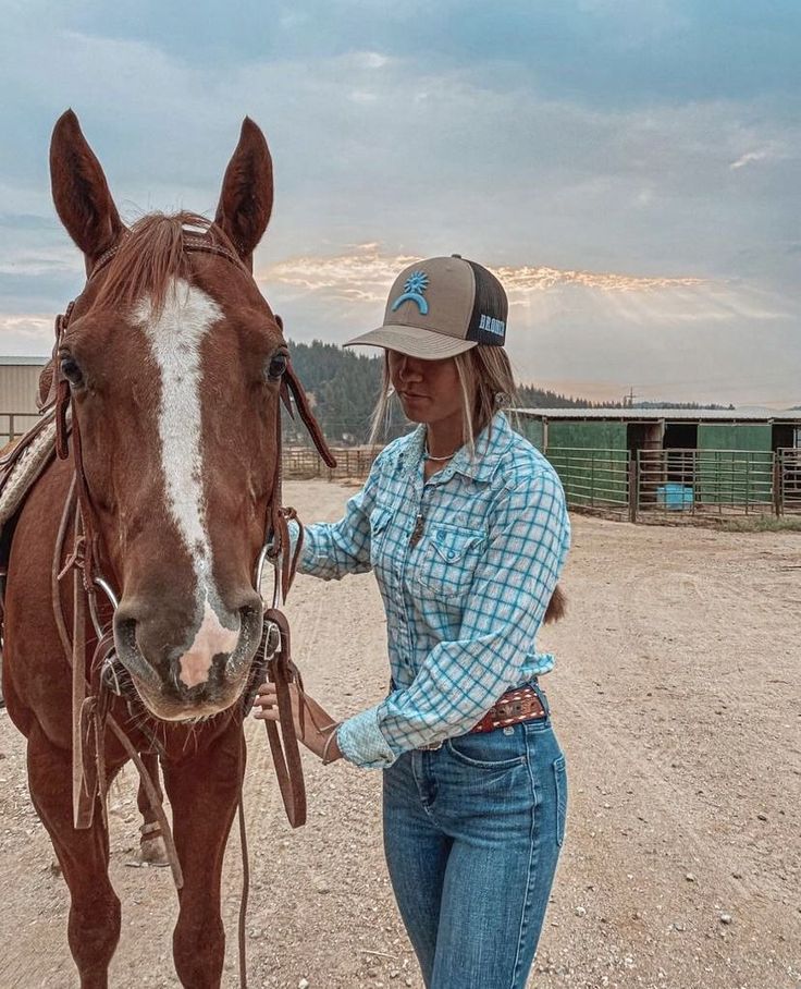 a woman leading a brown horse across a dirt field