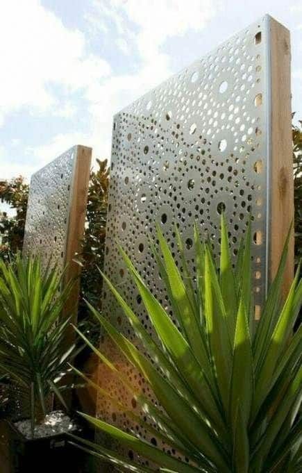 two large metal panels sitting next to each other in front of trees and plants on a sunny day