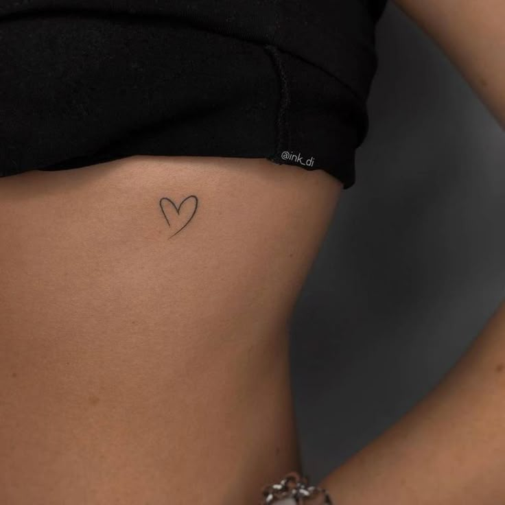 a woman with a small heart tattoo on her stomach