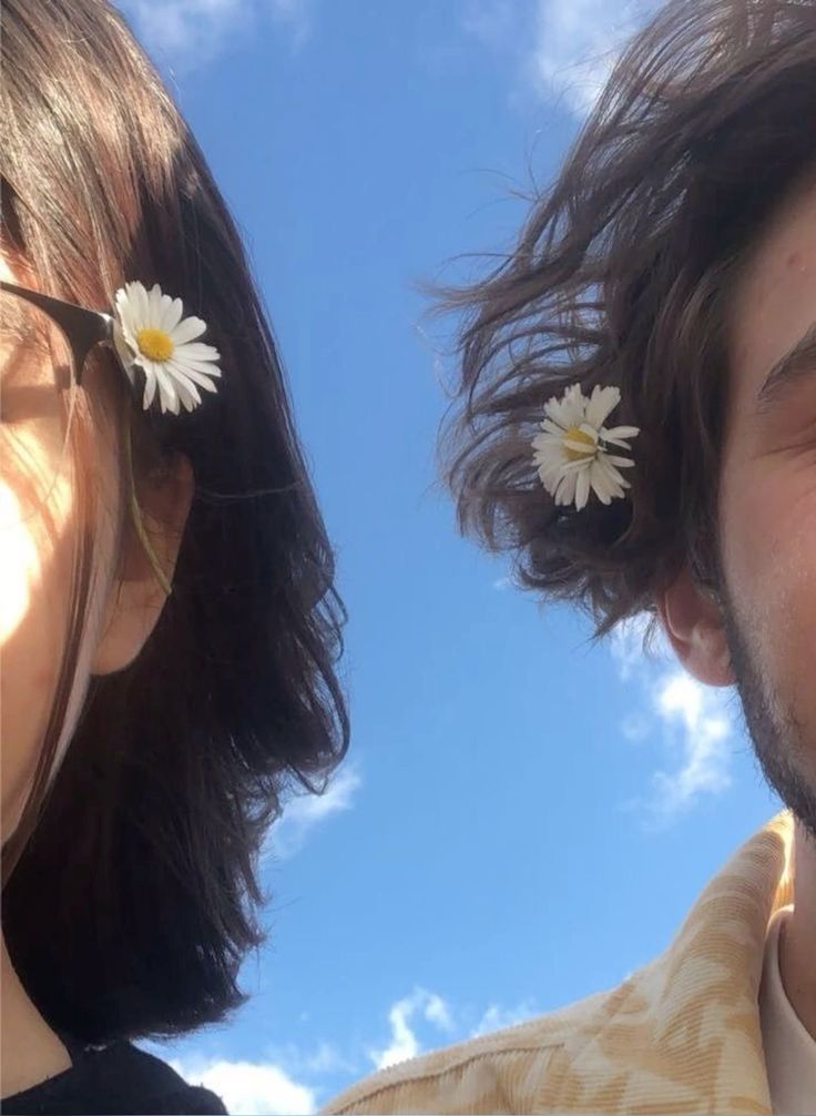 two people with flowers in their hair looking up at the sky and one person has his eyes closed