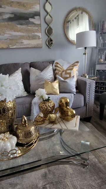 a living room filled with lots of furniture and gold accessories on top of a glass table