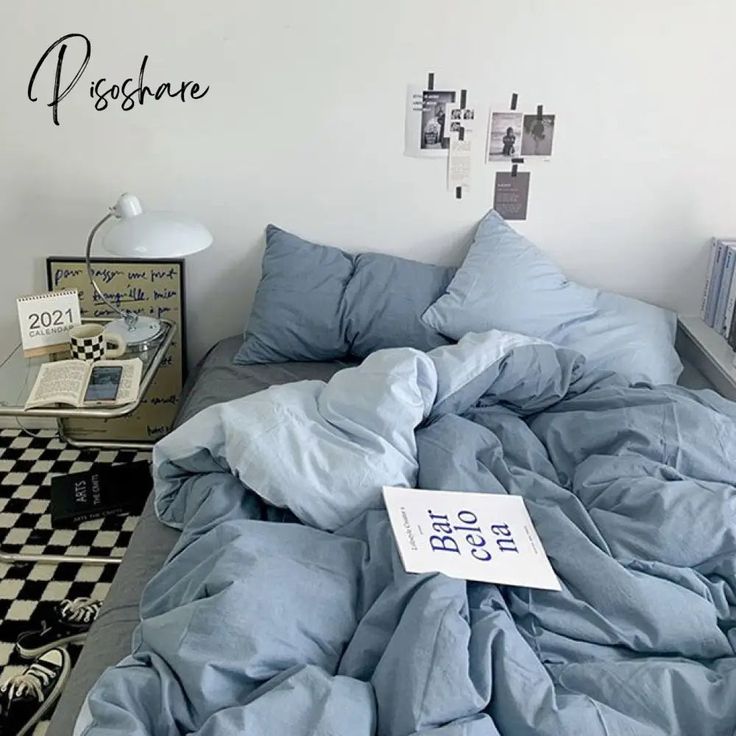 an unmade bed in a bedroom with blue sheets and checkerboard flooring