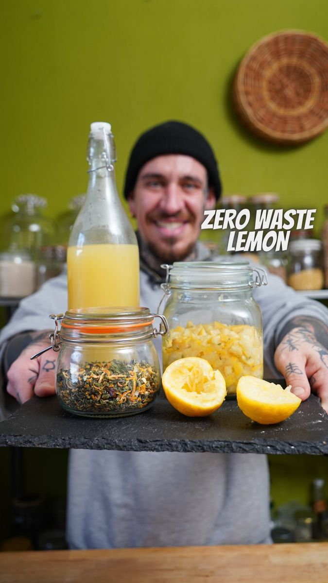 a man standing behind a counter filled with lemons and other food items on it