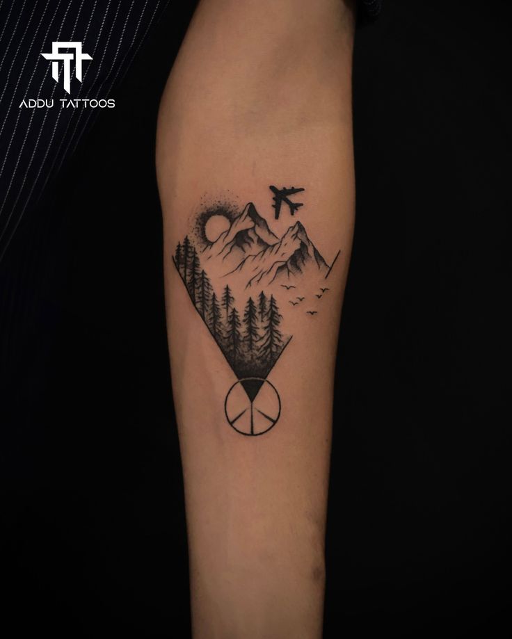 a man's arm with a mountain and forest tattoo on it