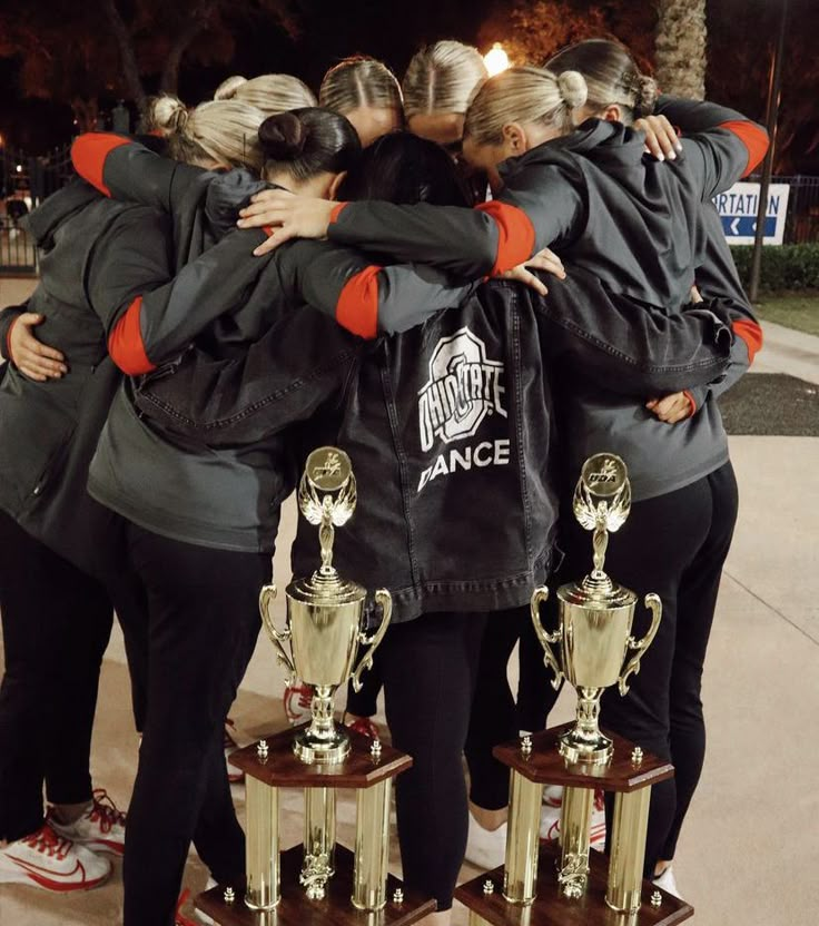 a group of women standing next to each other with their arms around each other and holding trophies